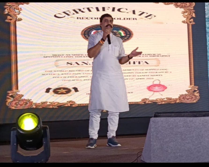 Sanjay Mehta speaking on stage with Record Holder certificate backdrop